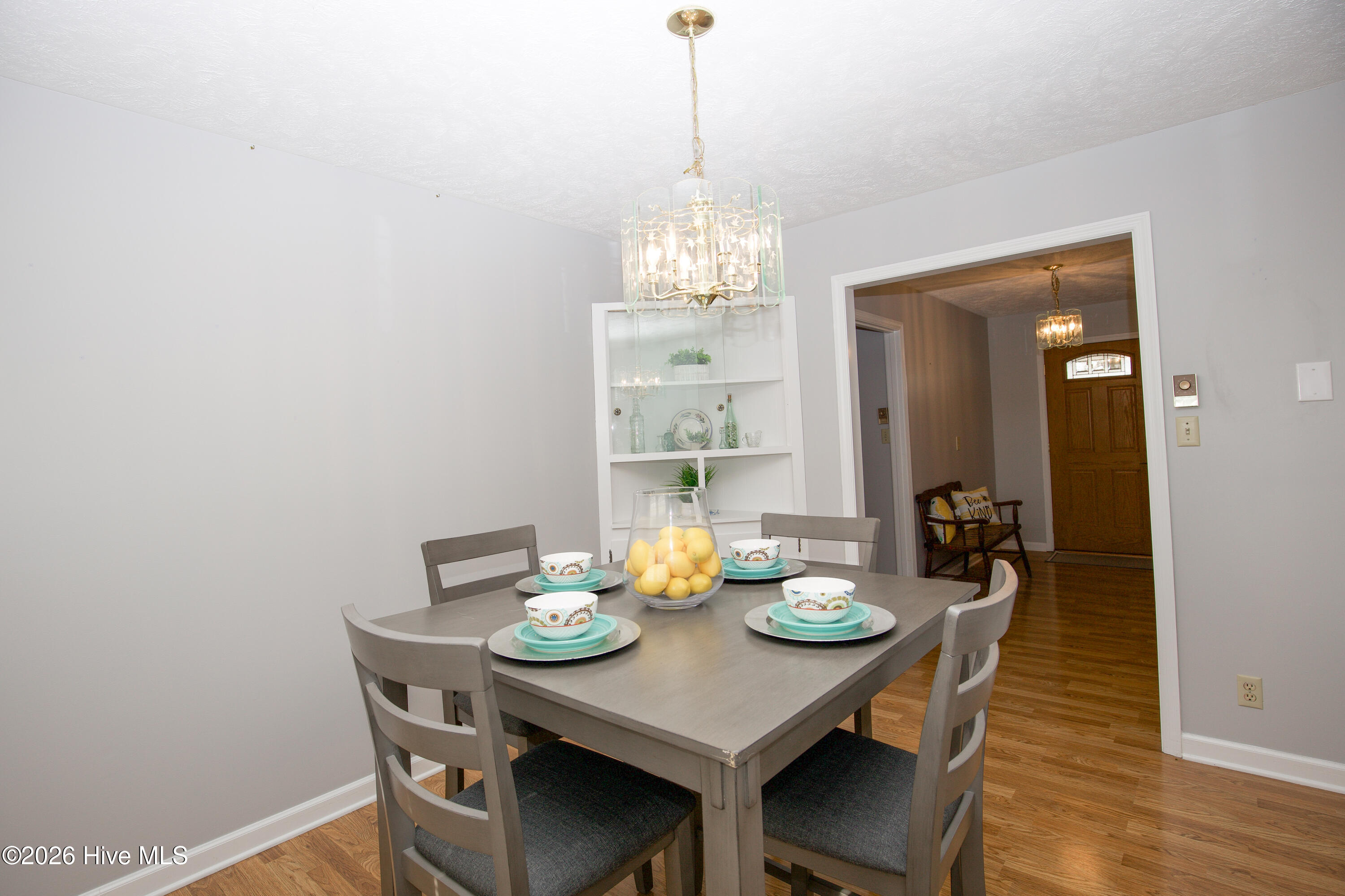 5068 Lobelia Road Vass, NC 28394 - Photo 16 of 70 This bright and inviting dining area offers a lovely view into the front entry, creating a welcoming and open feel. A classic chandelier adds a touch of elegance above the table, while the built-in shelving provides a perfect spot for displaying decorative pieces or storing essentials. The neutral color palette and wood-look floors make this space feel fresh and versatile, ready to suit any style or occasion. Whether you're hosting friends or enjoying a quiet meal at home, this dining area blends function and charm seamlessly.