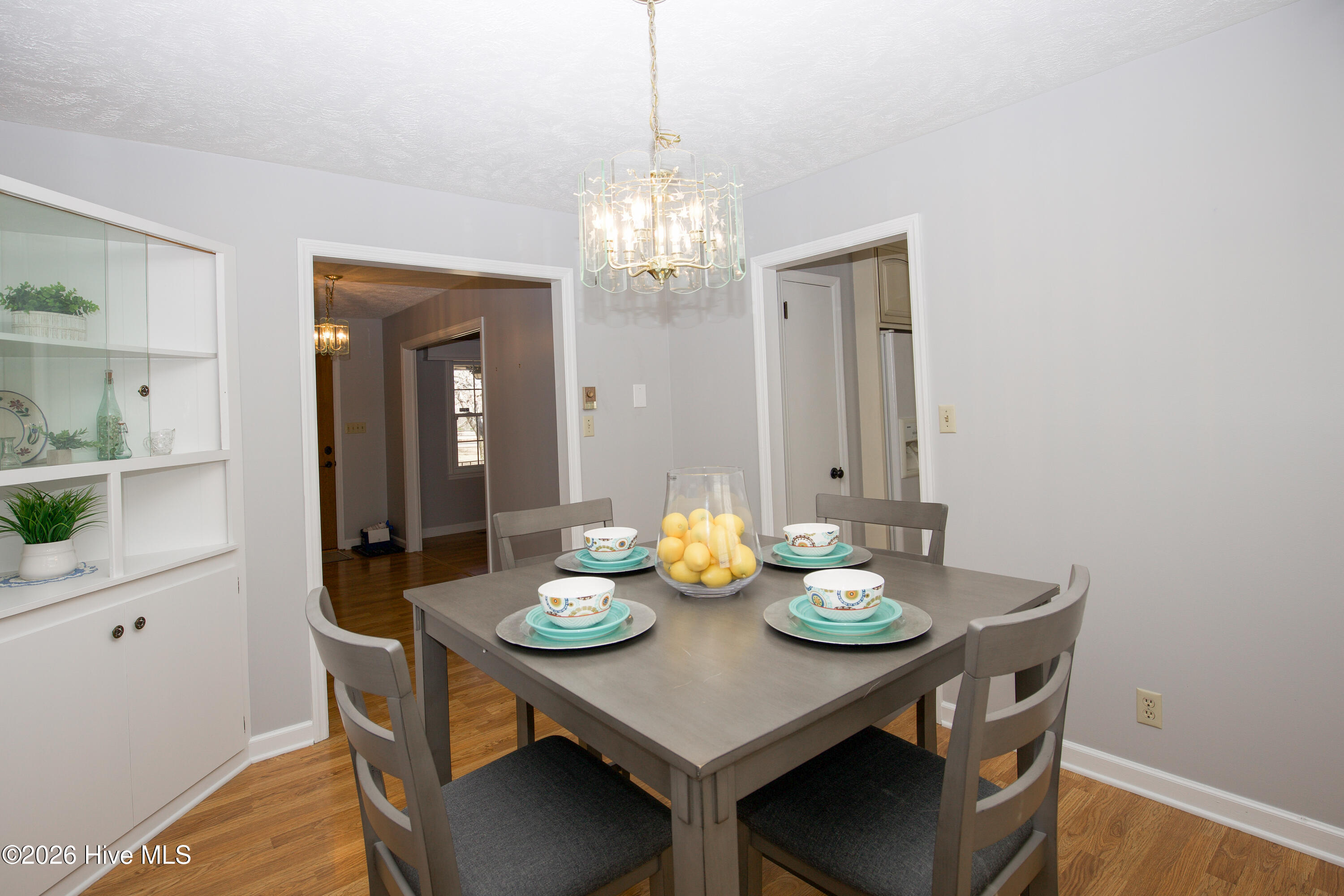 5068 Lobelia Road Vass, NC 28394 - Photo 17 of 70 Enjoy effortless flow from the dining area into both the kitchen and front entry in this thoughtfully designed space. The built-in hutch adds charm and function, offering storage and display space for your favorite dishware or décor. Neutral wall colors and rich wood-look flooring create a versatile setting for any dining style, while the central chandelier brings in timeless elegance. With easy access to the heart of the home and beyond, this space is ideal for both casual meals and special gatherings.