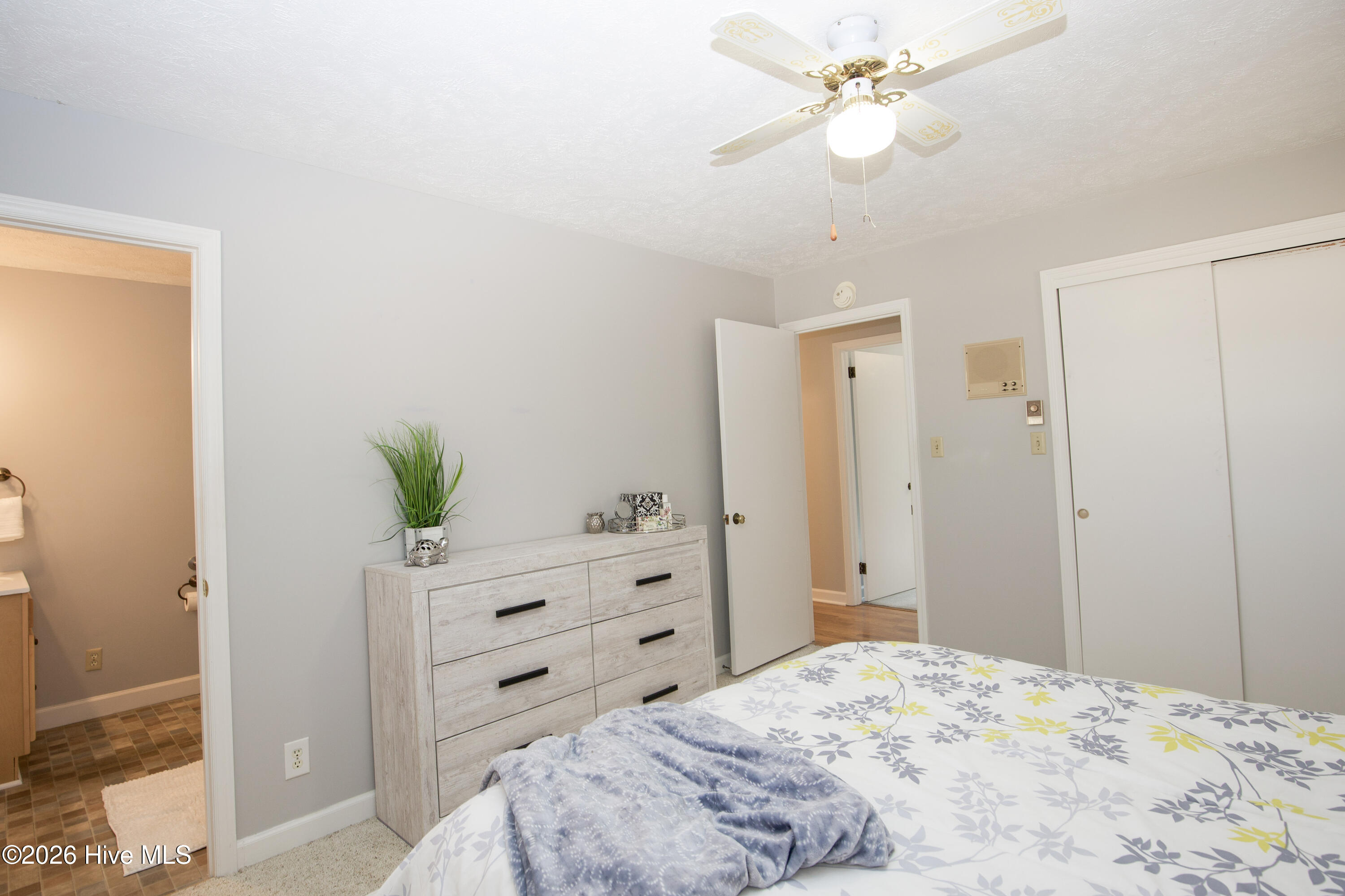 5068 Lobelia Road Vass, NC 28394 - Photo 20 of 70 Another angle of the spacious primary bedroom reveals large dual closets with sliding doors, offering generous storage. A neutral palette enhances the light, airy feel, while the ensuite bathroom is just steps away for added convenience. The ceiling fan adds comfort to this tranquil and functional retreat.