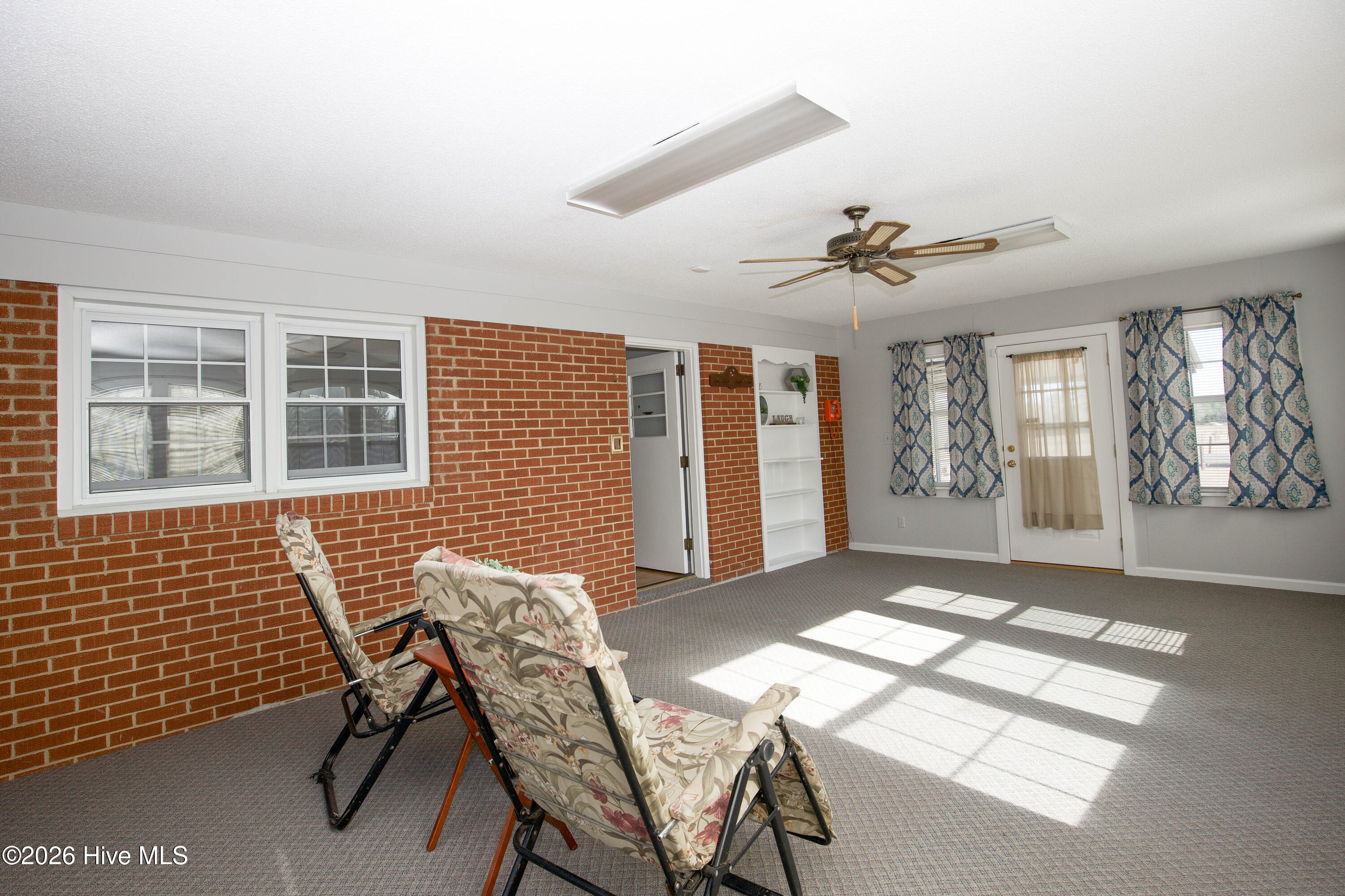 5068 Lobelia Road Vass, NC 28394 - Photo 33 of 70 Sunlight streams into the spacious Carolina Room, creating a bright and uplifting atmosphere year-round. This versatile space, with its warm brick walls and direct access to the backyard, is ideal for morning coffee, casual entertaining, or a peaceful reading nook. The ceiling fan and large windows ensure comfort and fresh air throughout the seasons.