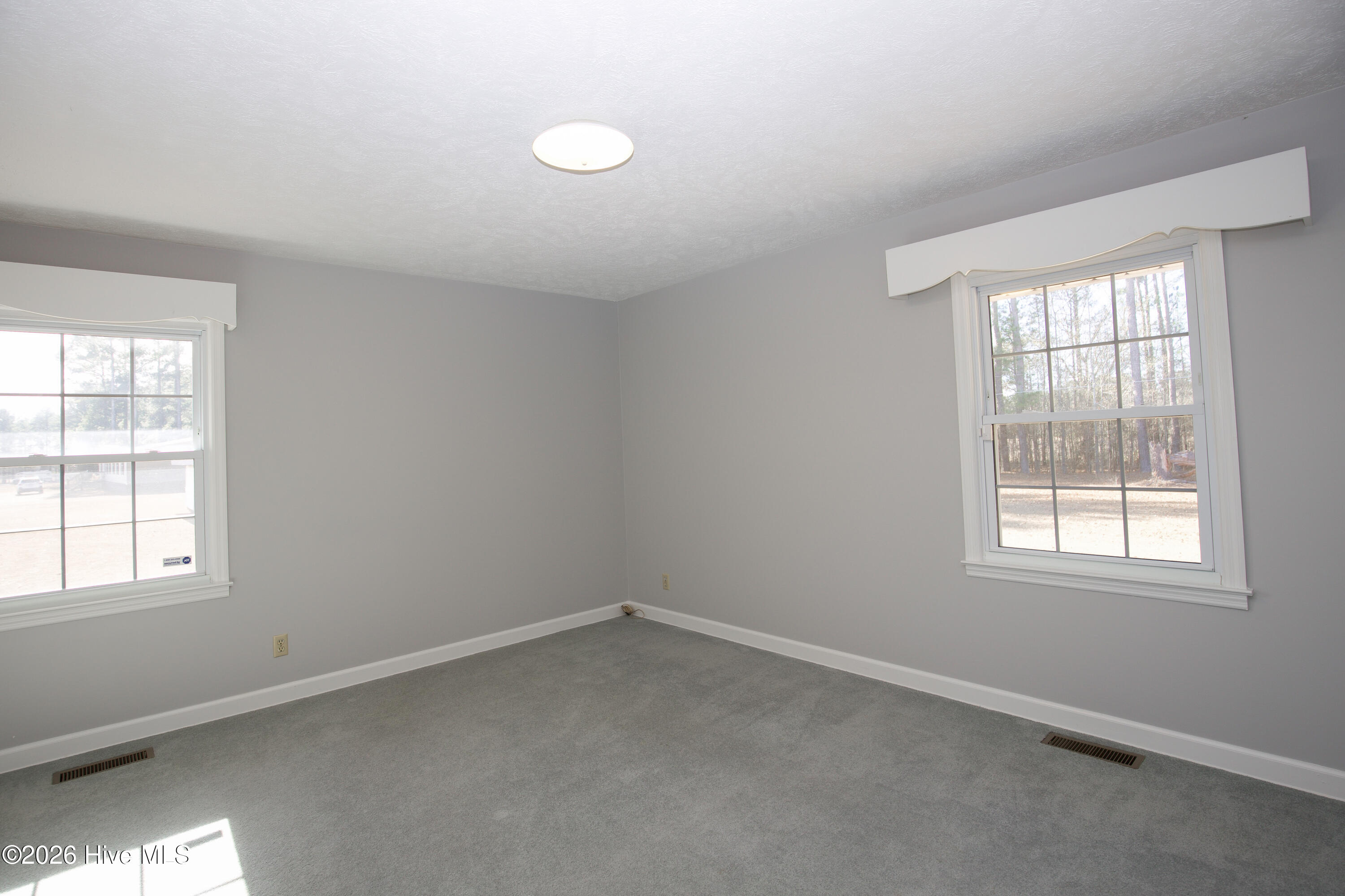 5068 Lobelia Road Vass, NC 28394 - Photo 37 of 70 Another view of Bedroom #2, showcasing two large windows that fill the room with natural light and offer views of both the backyard and side yard. Soft carpeting and neutral paint create a calming atmosphere perfect for rest, work, or play.