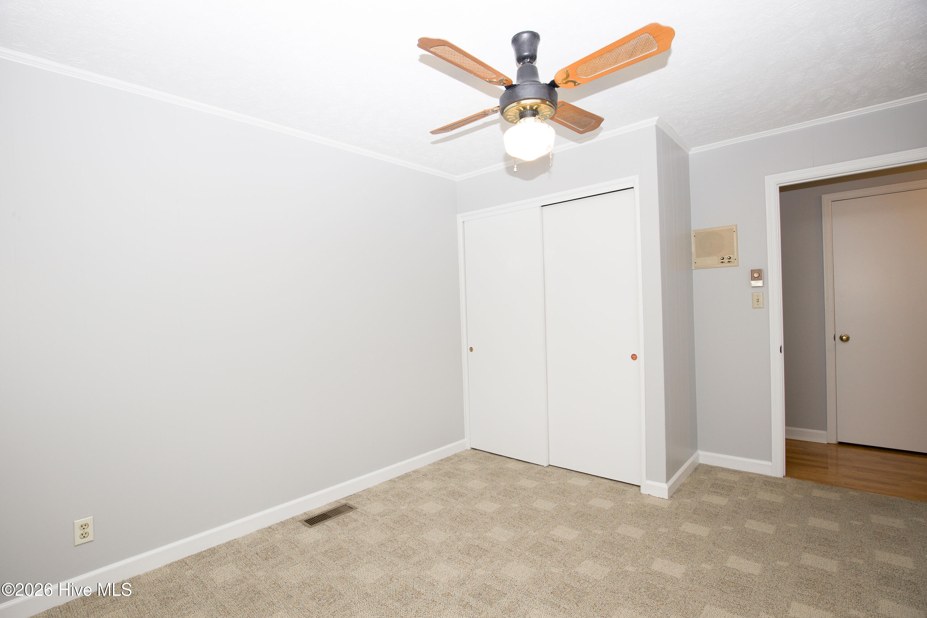 5068 Lobelia Road Vass, NC 28394 - Photo 41 of 70 Another angle of Bedroom #3, highlighting the spacious closet with sliding doors and charming ceiling fan. Neutral paint and carpet tones provide a fresh canvas for personal style. Central air vent and wall heater offer flexible comfort options year-round.