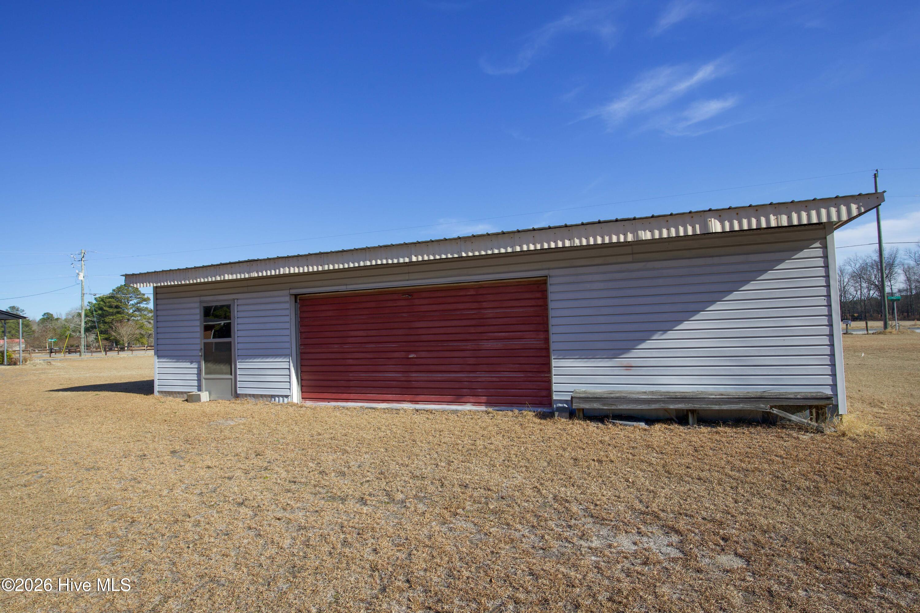 5068 Lobelia Road Vass, NC 28394 - Photo 66 of 70 This detached garage at 5068 Lobelia Rd features a bold red roll-up door and side entry access. Positioned conveniently near the home, it provides ample room for vehicle storage, workshop activities, or additional storage needs. The structure sits on a spacious section of the lot, offering easy access from the adjacent driveway and plenty of clearance for larger equipment or projects.
