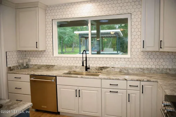 a kitchen with granite countertop white cabinets and a window