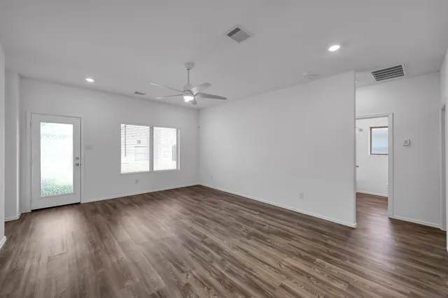 an empty room with wooden floor and windows