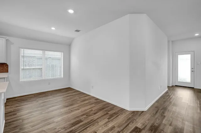 a kitchen with stainless steel appliances granite countertop a stove a sink and white cabinets with wooden floor