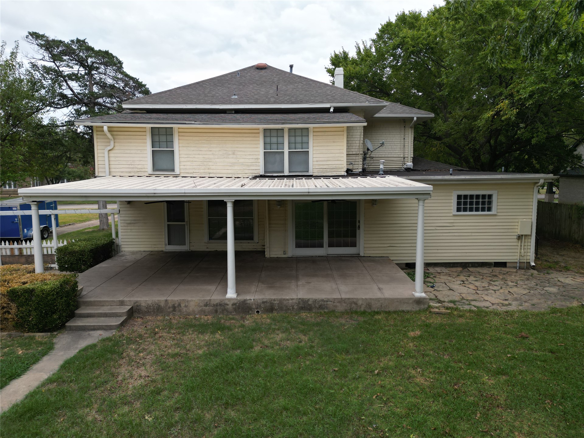 219 F Street Southwest Ardmore, OK 73401 - Photo 48 of 58 Expansive concrete patio with a covered porch structure, dual sliding glass doors, and a manicured lawn