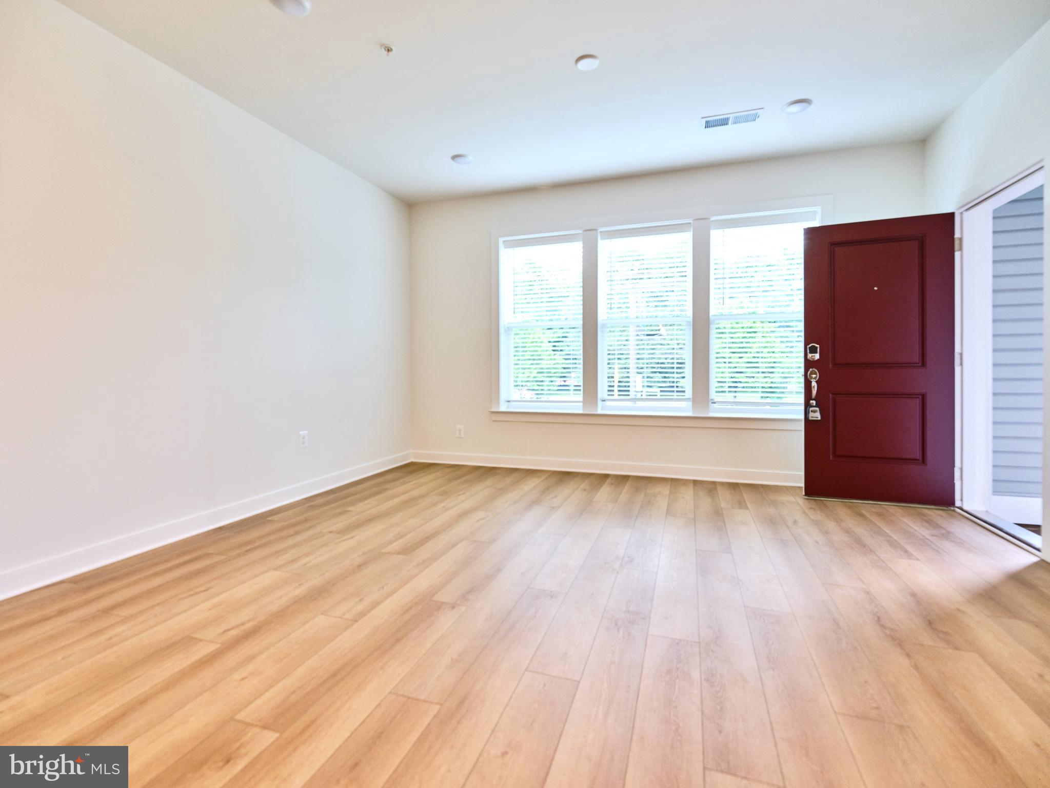 16076 Frederick Road Rockville, MD 20850 - Photo 3 of 30 an empty room with wooden floor and windows