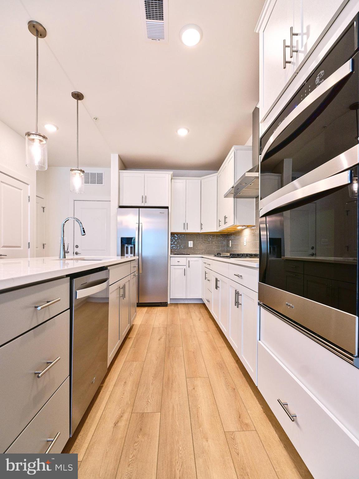 16076 Frederick Road Rockville, MD 20850 - Photo 7 of 30 a large kitchen with stainless steel appliances kitchen island granite countertop a stove a sink and white cabinets with wooden floor