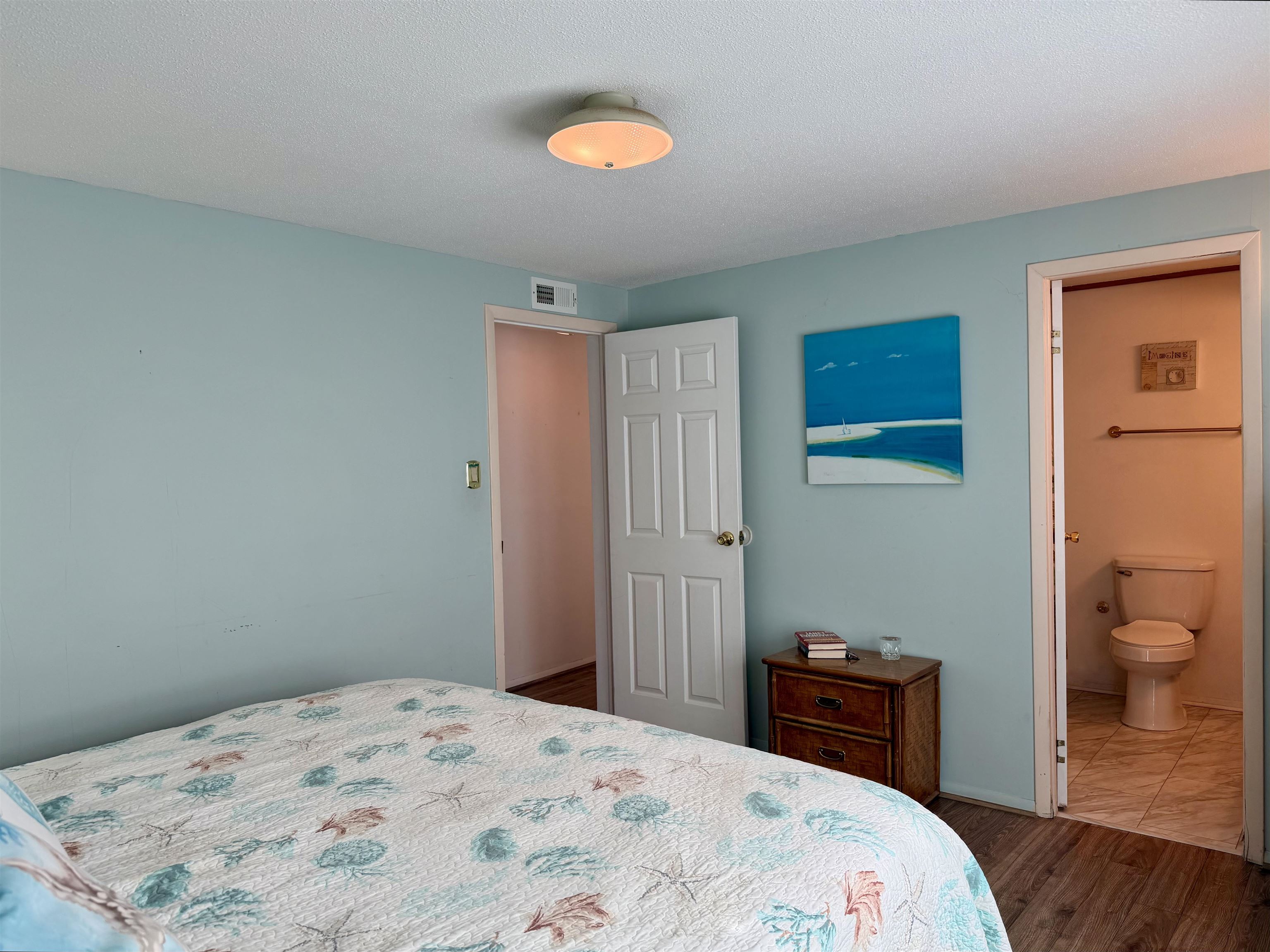 1980 Lark Surfside Beach, SC 29575 - Photo 15 of 30 Bedroom with a textured ceiling, dark wood-style flooring, and connected bathroom