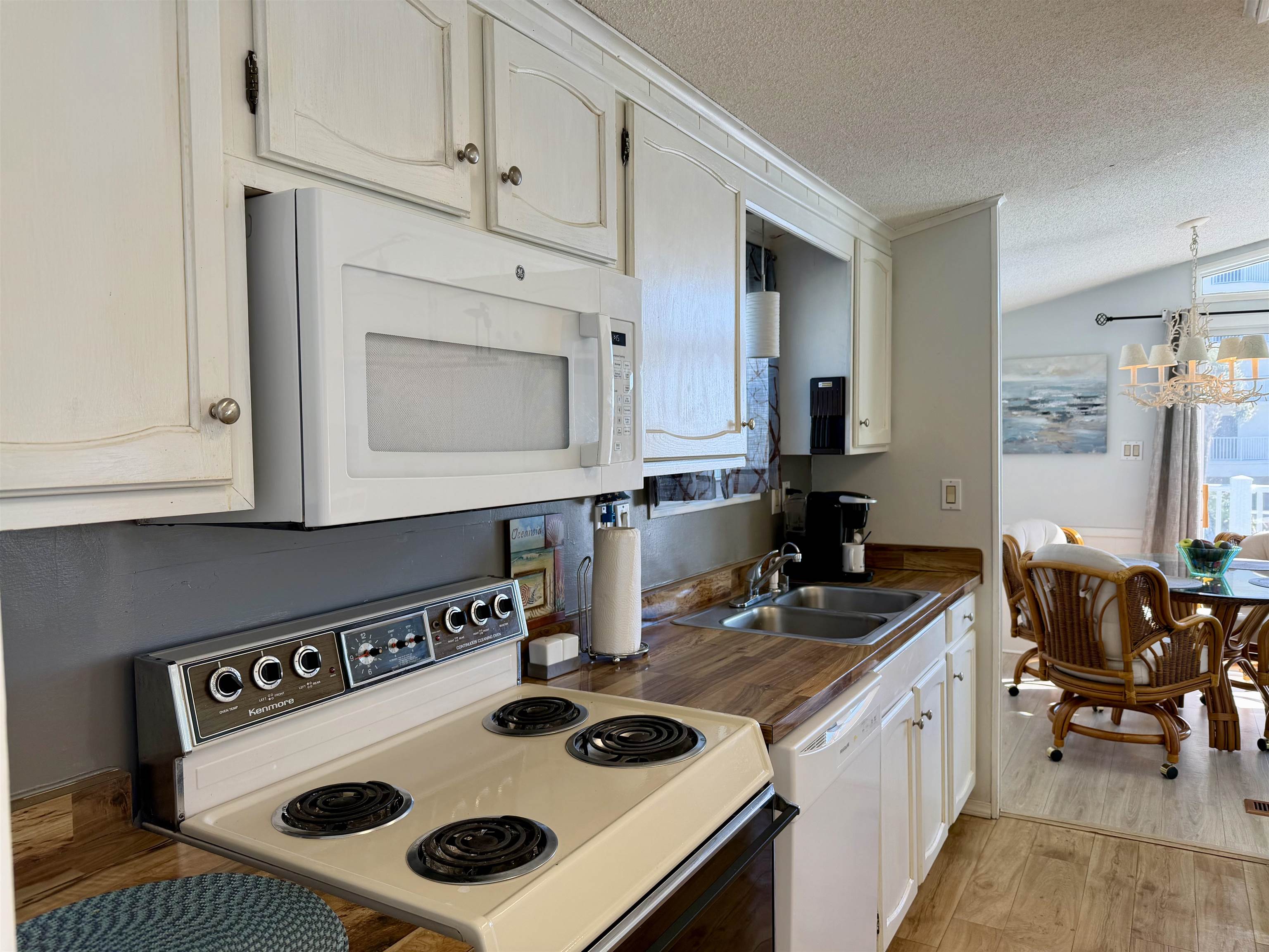 1980 Lark Surfside Beach, SC 29575 - Photo 3 of 30 Kitchen featuring white appliances, dark countertops, a textured ceiling, light wood-style floors, and a chandelier