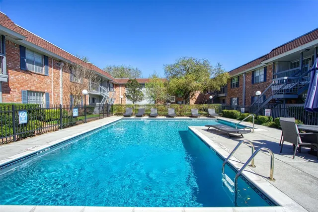 a view of swimming pool with outdoor seating and house in the background