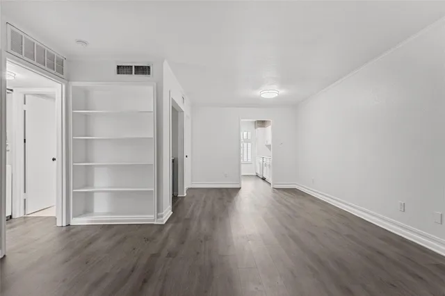 a view of an empty room with wooden floor and closet