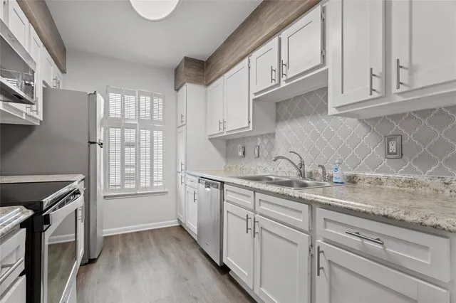 a kitchen with stainless steel appliances granite countertop white cabinets and a sink