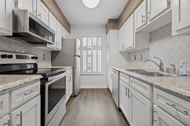 a kitchen with stainless steel appliances granite countertop a stove a sink and a microwave