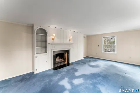 an empty room with windows and fireplace