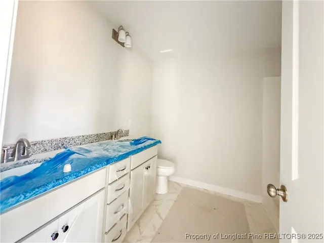 a bathroom with a granite countertop sink a toilet and a mirror