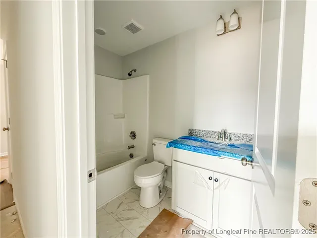 a bathroom with a granite countertop sink a toilet and shower