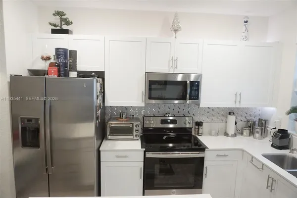 a kitchen with stainless steel appliances a refrigerator a sink a stove and cabinets