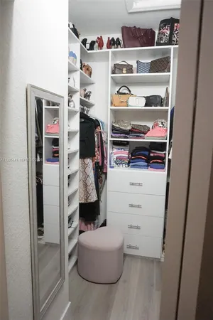 a view of walk in closet with clothes and shoes