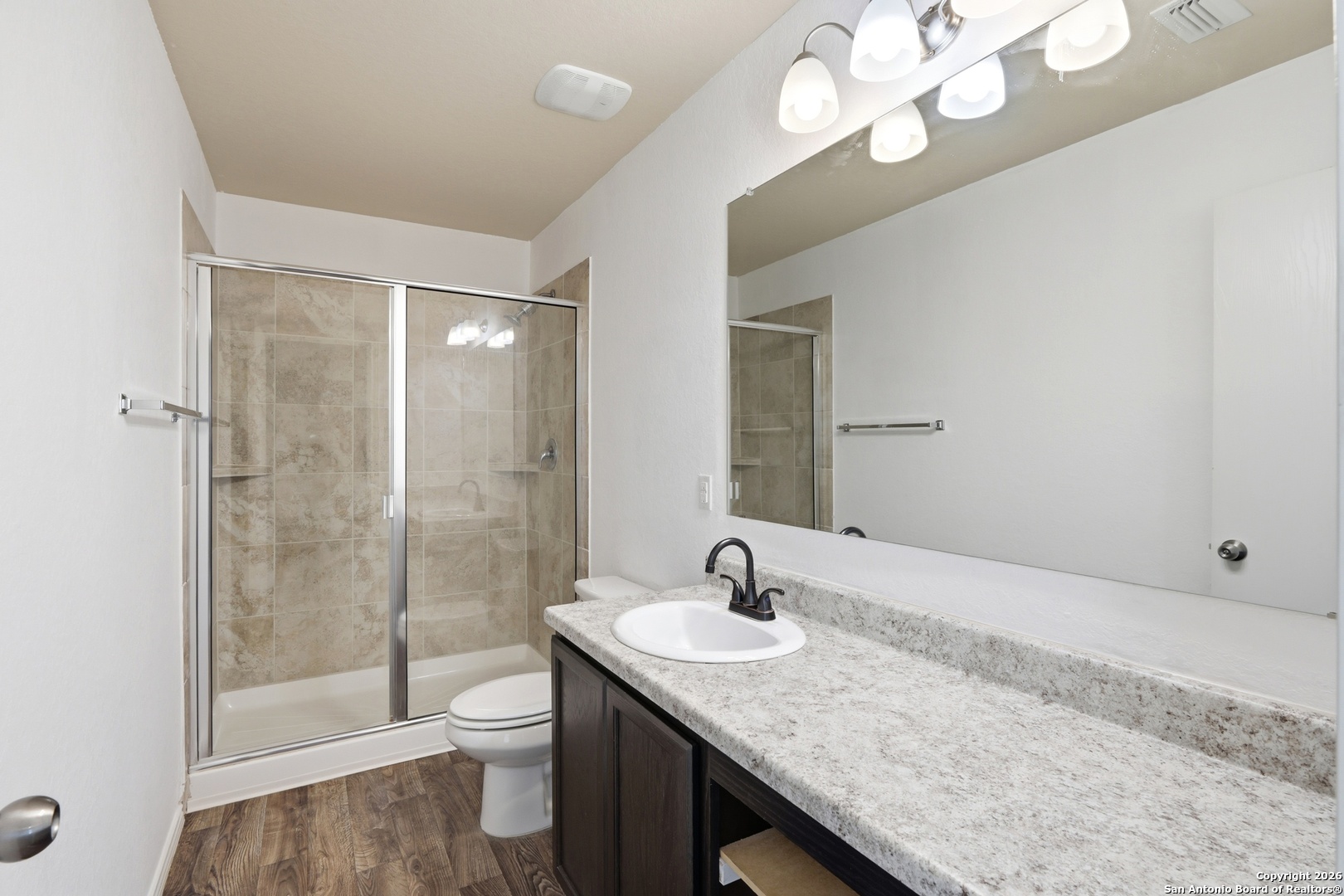9713 Sandy Rdg Way San Antonio, TX 78239 - Photo 24 of 39 a bathroom with a granite countertop sink a toilet and shower