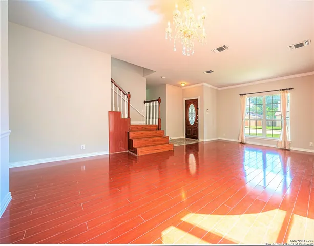 a view of an empty room with window and wooden floor