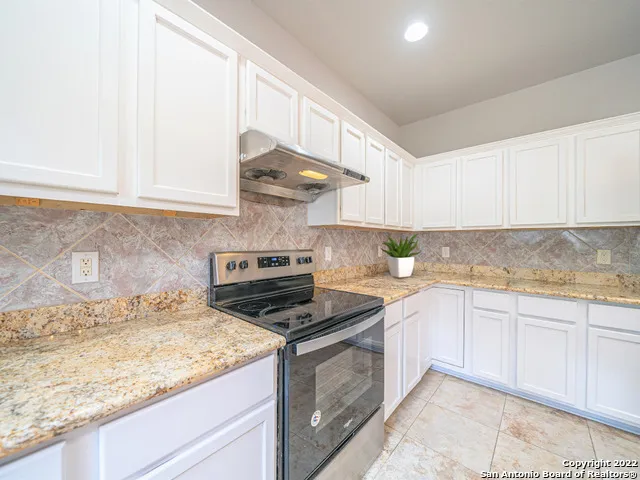a kitchen with granite countertop a sink a stove and cabinets