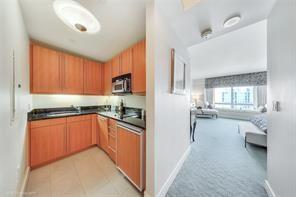 1435 Brickell Avenue, Unit 3211 Miami, FL 33131 - Photo 11 of 16 a kitchen with stainless steel appliances granite countertop a refrigerator a sink dishwasher a stove and white cabinets with wooden floor