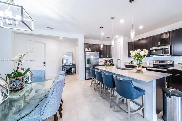 a kitchen with stainless steel appliances a sink dishwasher a stove top oven a refrigerator with wooden floor