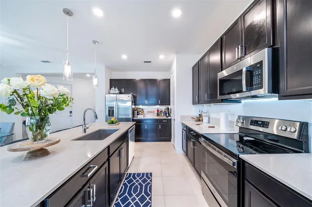 a kitchen with stainless steel appliances a sink dishwasher a stove top oven a refrigerator with wooden floor