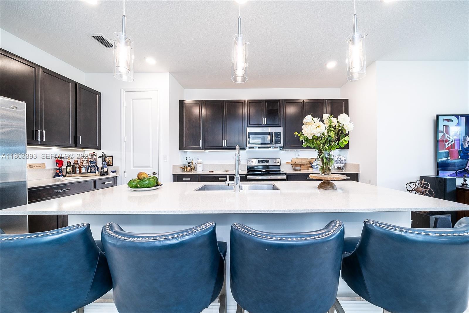 4230 Rosa Drive Deerfield Beach, FL 33064 - Photo 9 of 52 a kitchen with kitchen island a appliances a sink and a living room view