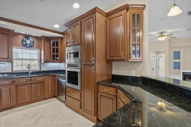 a kitchen with stainless steel appliances granite countertop a refrigerator a stove and a sink with wooden cabinets