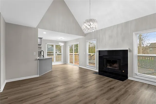 an empty room with wooden floor fireplace cabinet and windows