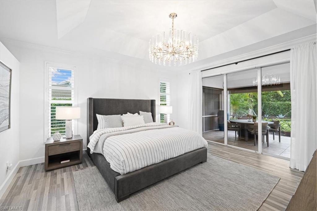 2032 Prince Drive Naples, FL 34110 - Photo 16 of 44 a spacious bedroom with a large bed and a chandelier