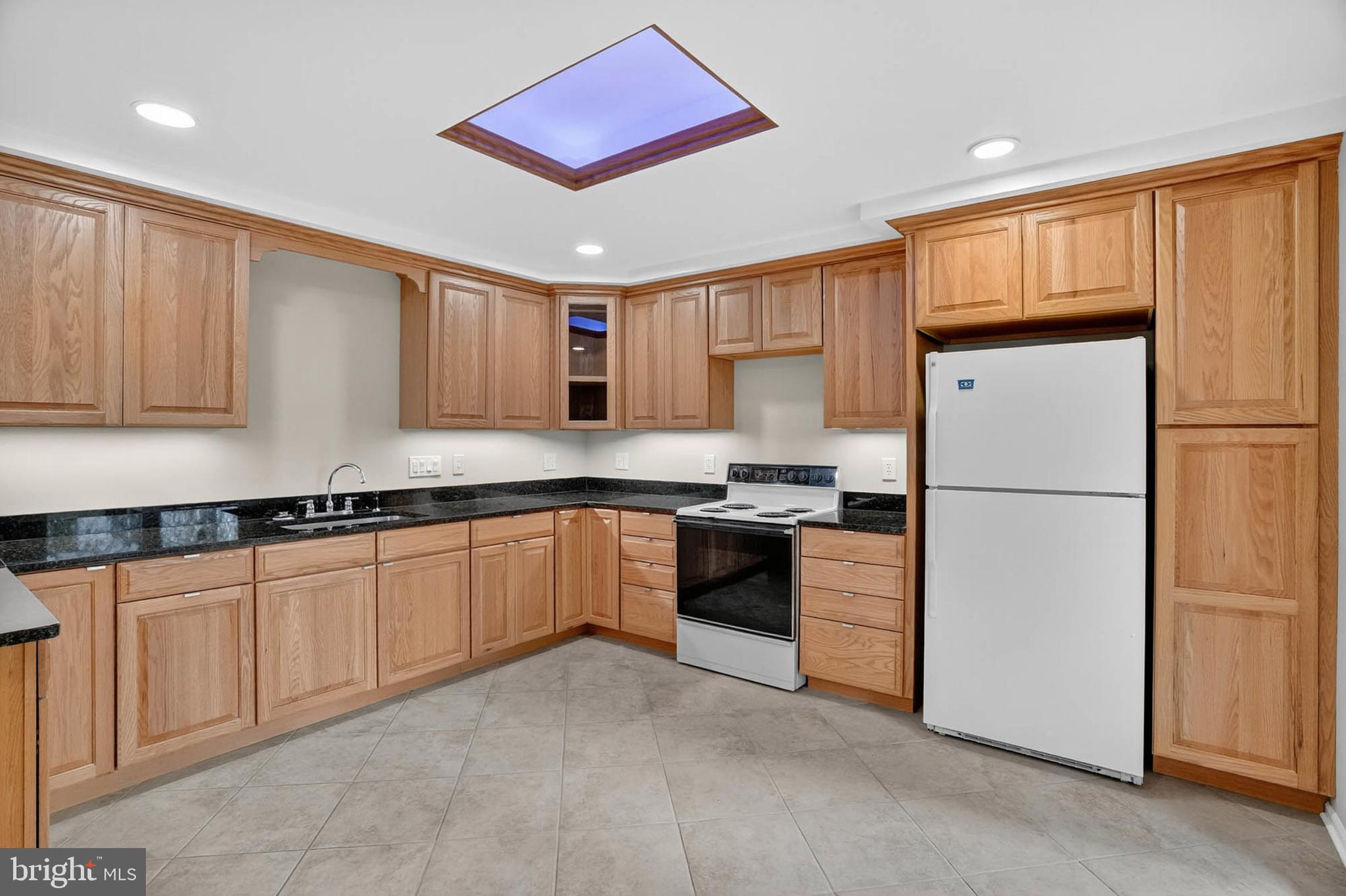 8203 Willow Street Laurel, MD 20707 - Photo 12 of 41 a kitchen with granite countertop a refrigerator a sink and white cabinets