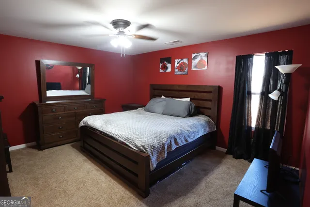 a bedroom with a bed and a lamp on dresser