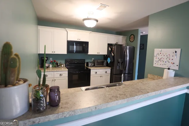 a kitchen with stainless steel appliances kitchen island granite countertop a refrigerator stove top oven and sink