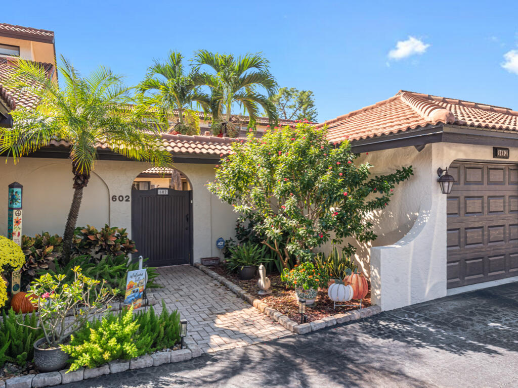 602 Augusta Boulevard, Unit 3 Naples, FL 34113 - Photo 1 of 8 a front view of a house with a yard and potted plants