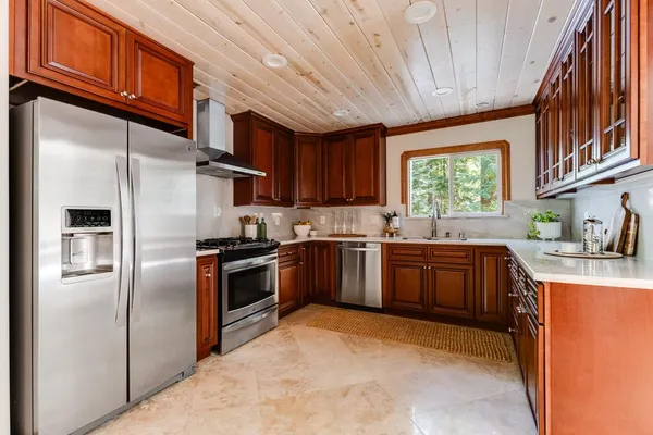 a kitchen with stainless steel appliances granite countertop a refrigerator a sink dishwasher a stove top oven a refrigerator and cabinets