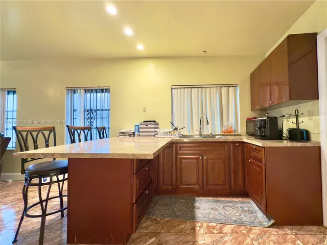 a kitchen with stainless steel appliances granite countertop a stove a sink dishwasher and a refrigerator with wooden cabinets