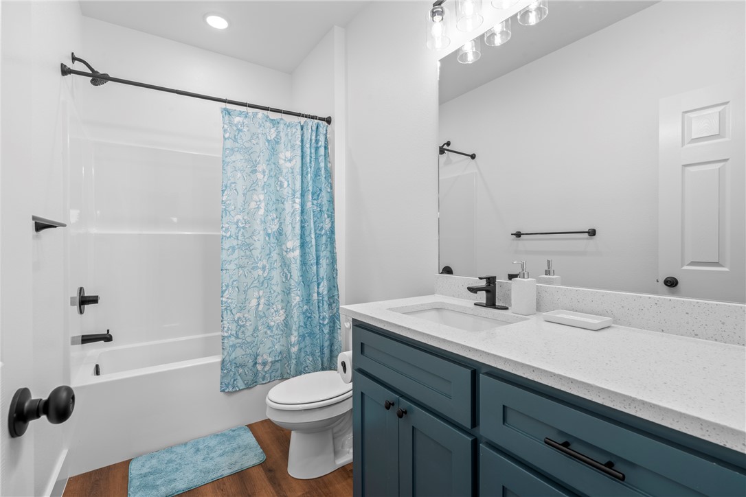 16556 East Hewitt Springs Road Springdale, AR 72764 - Photo 52 of 60 Bathroom featuring a white tub/shower combination, dark teal vanity with a white speckled countertop, and wood-finish flooring