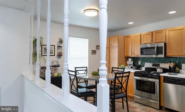 a kitchen with stainless steel appliances a table chairs and a refrigerator