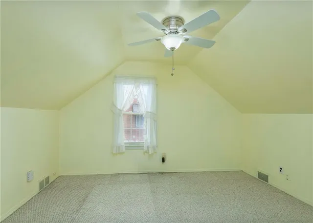 an empty room with a chandelier fan and windows