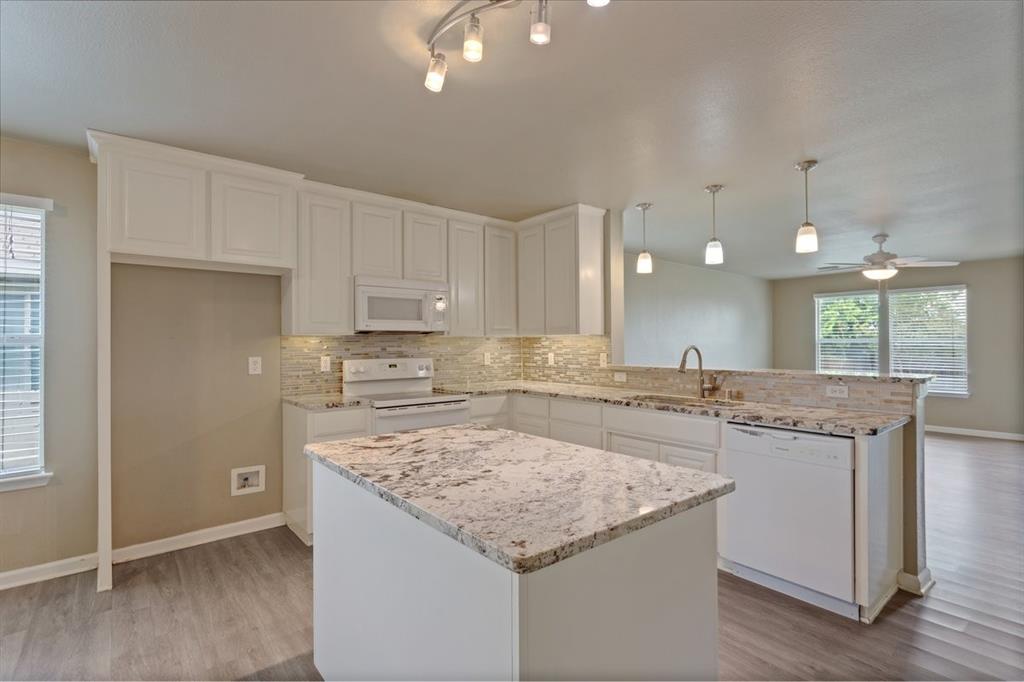 1005 Live Oak Drive Anna, TX 75409 - Photo 2 of 29 Kitchen featuring white appliances, decorative light fixtures, white cabinets, backsplash, and a peninsula