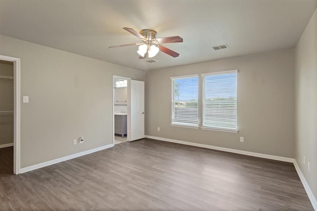 1005 Live Oak Drive Anna, TX 75409 - Photo 8 of 29 Unfurnished bedroom with a walk in closet, dark wood-style flooring, ceiling fan, and connected bathroom