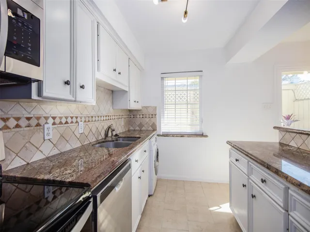a kitchen with granite countertop a sink stove and cabinets