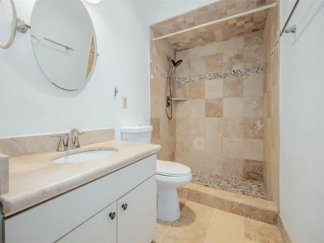a bathroom with a granite countertop sink a toilet and shower