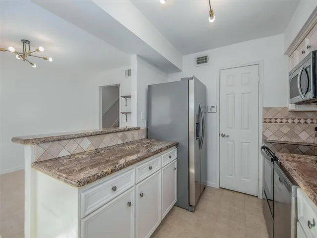 a view of a kitchen island with stainless steel appliances granite countertop furniture and a refrigerator