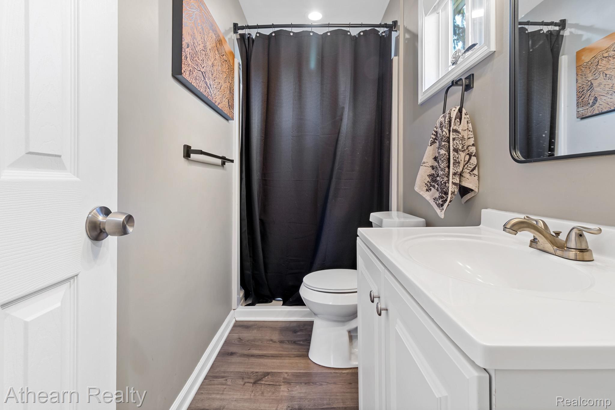5079 West Thompson Road Linden, MI 48451 - Photo 23 of 27 Modern bathroom featuring a white vanity with ample storage, white quartz countertop, and brushed nickel faucet