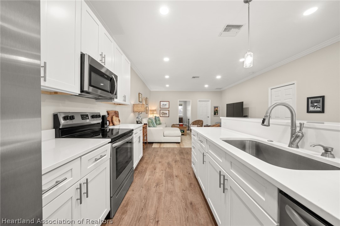 4734 Haw Branch Road, Unit 110 Sebring, FL 33875 - Photo 11 of 50 a large kitchen with stainless steel appliances granite countertop a lot of counter space and wooden floors